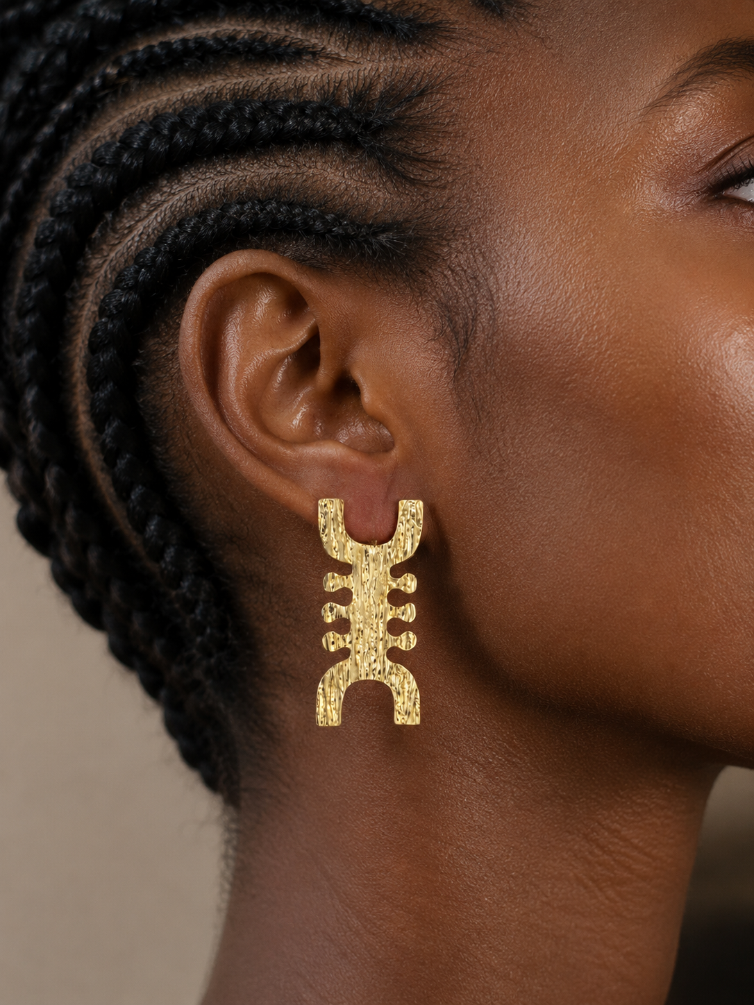 Gros plan sur une femme noire portant les boucles d’oreilles africaines NIT en bronze doré à l’or – collection Saafara fabriquée à la main au Sénégal par Kaolack Créations