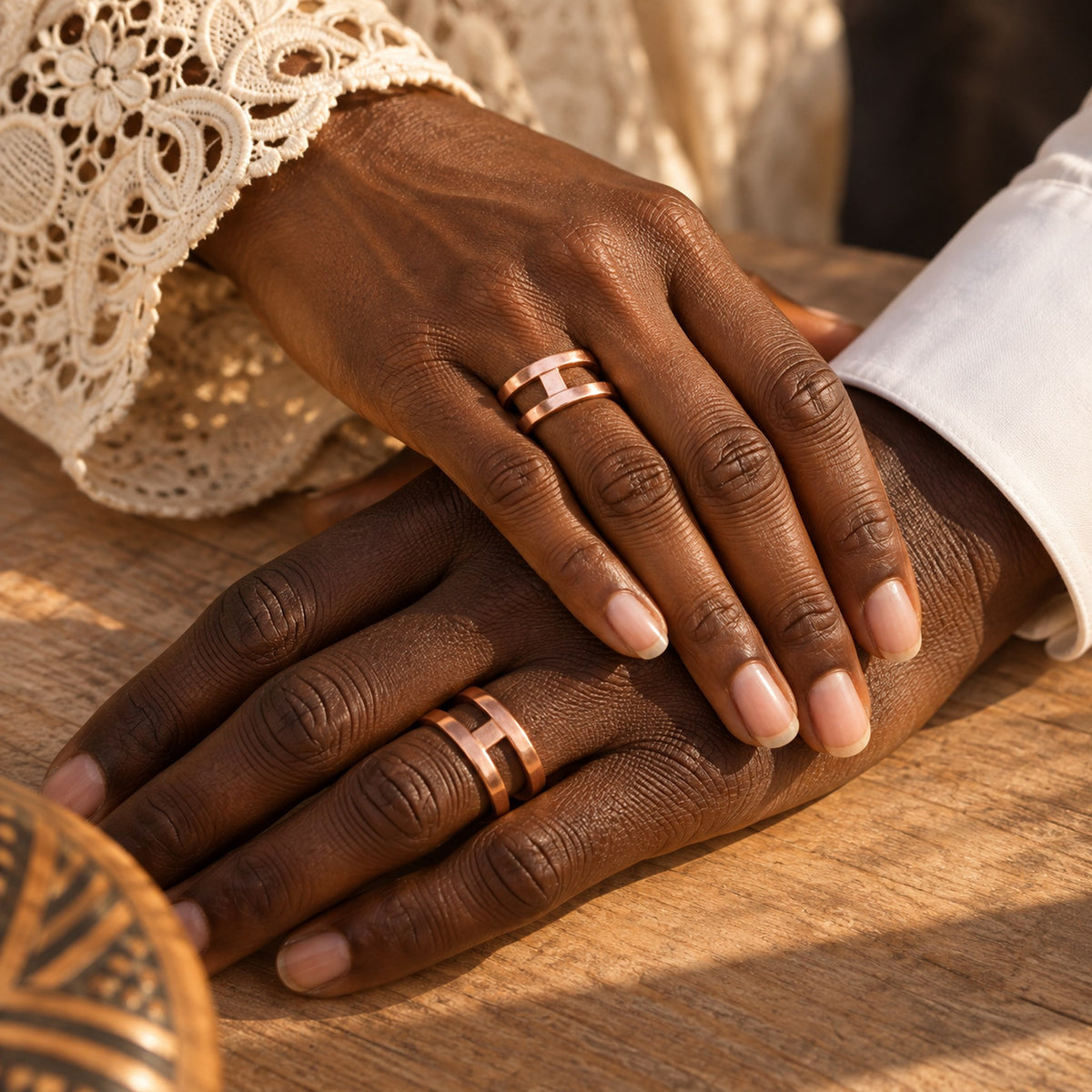 Deux mains, d'une femme et d'un homme, portant la bague Lisanga en cuivre