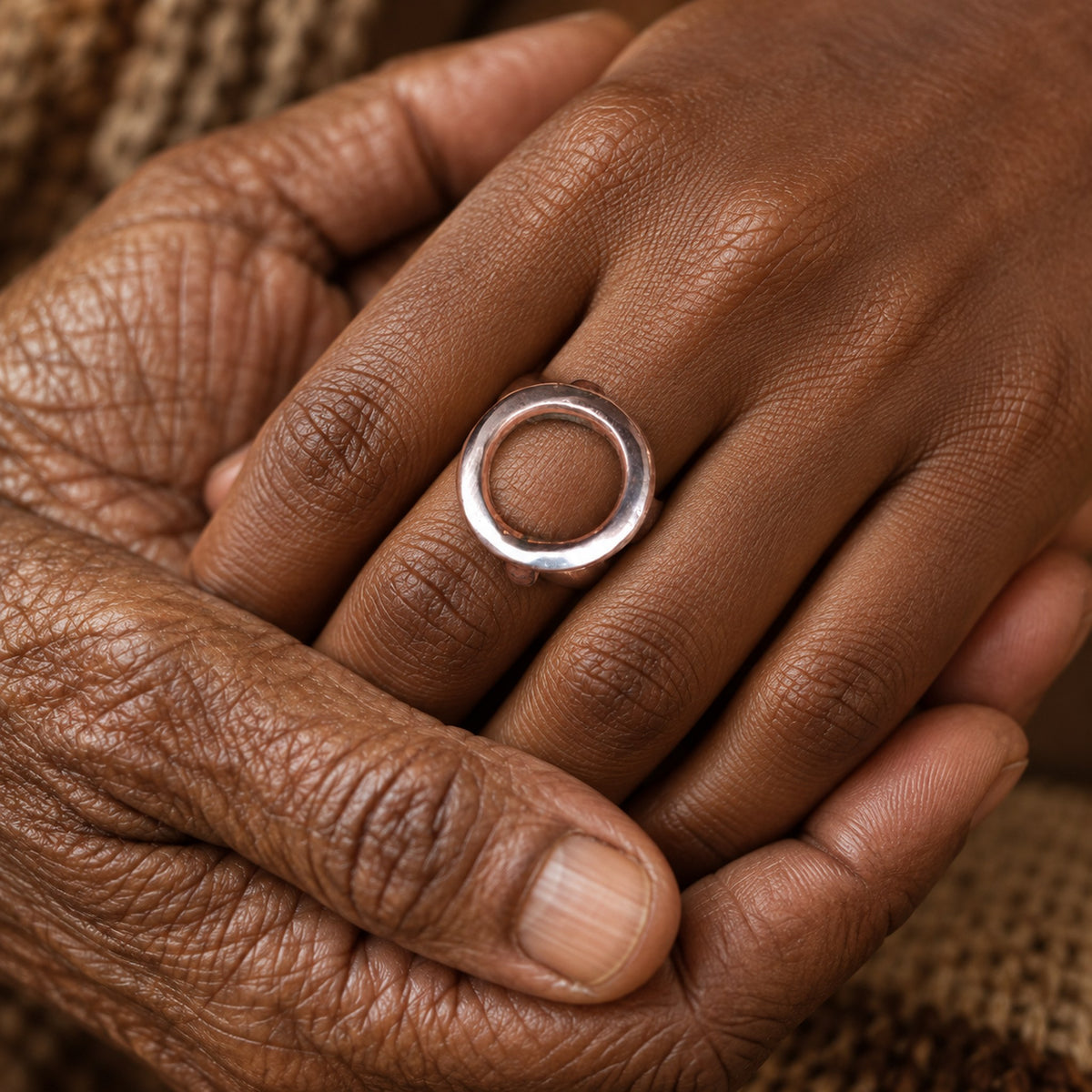 Bague Oshupa en cuivre portée à la main, deux mains réunies