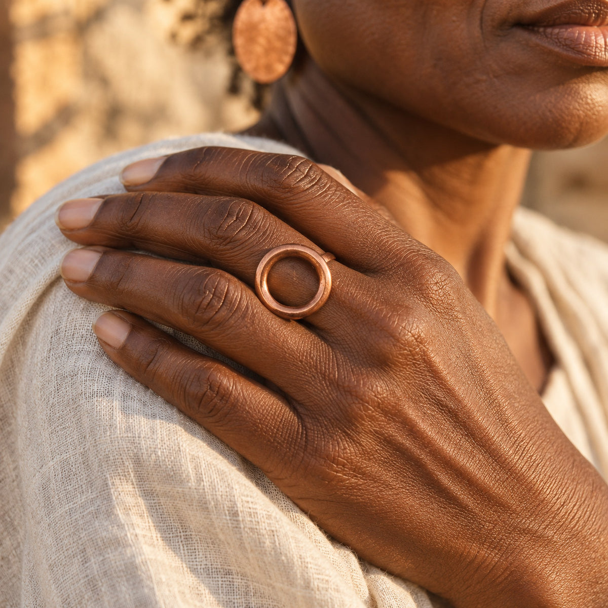 Main de femme portant la bague Oshupa en cuivre, posée sur l'épaule