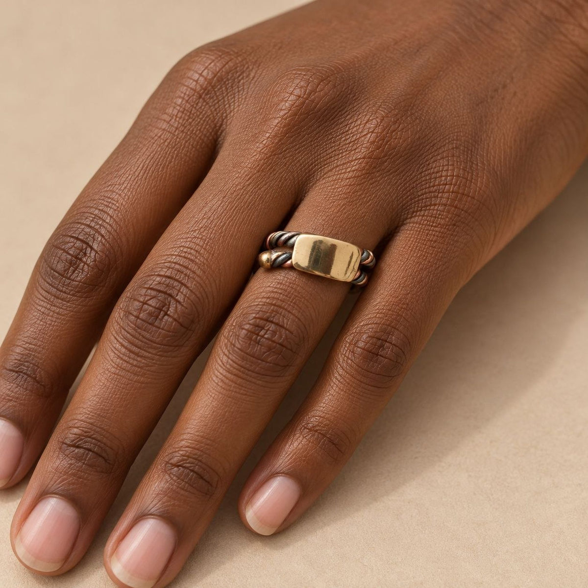 Bague sénégalaise Ndiaxass portée à l'annulaire d'une main de femme noire, plaque en bronze poli