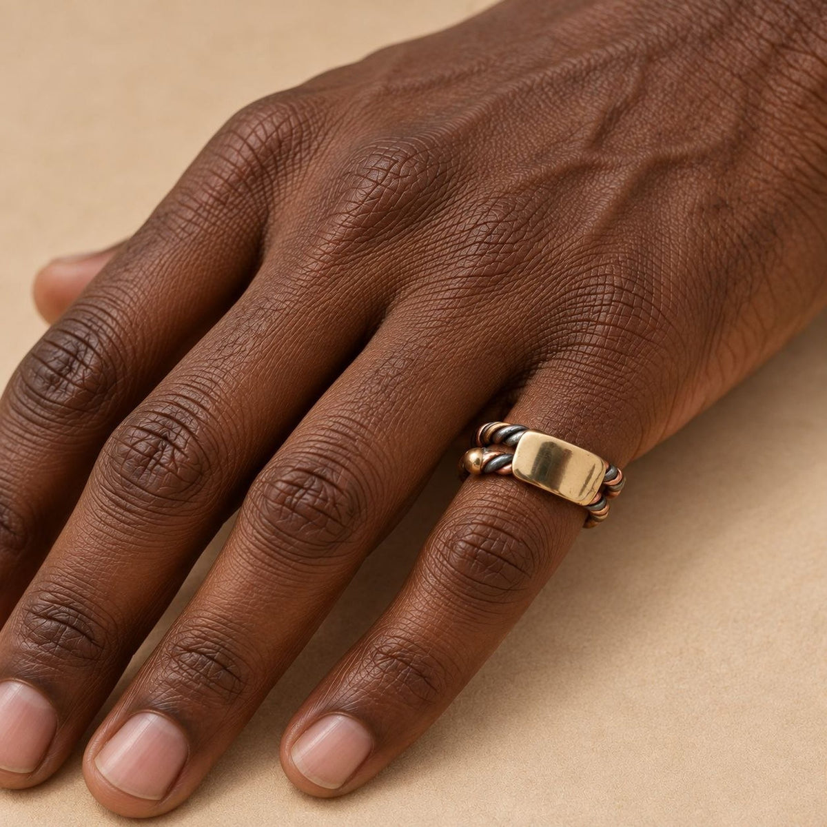 Bague sénégalaise Ndiaxass portée par un homme noir, allure de chevalière, plaque en bronze et torsade trois métaux
