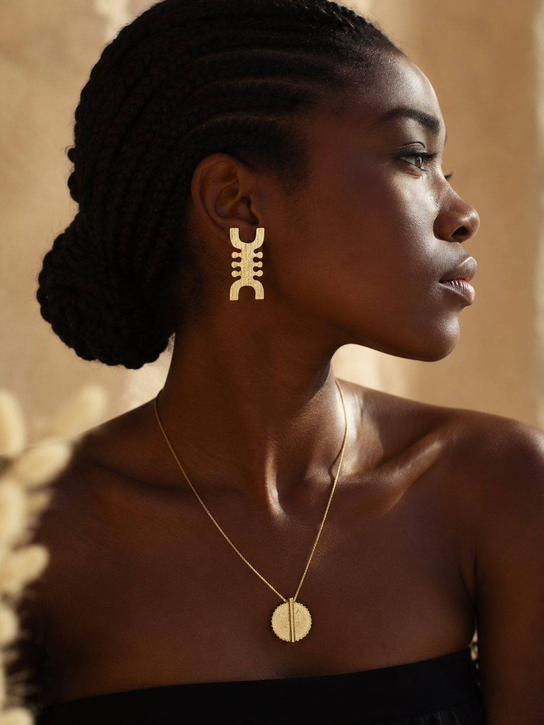 Boucles d’oreilles africaines NIT en bronze doré portées par une femme noire élégante aux tresses plaquées, bijou artisanal fabriqué à la main au Sénégal, collection Saafara Kaolack Créations