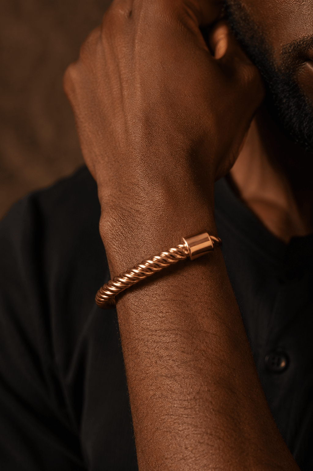 Bracelet Perem Torsadé en cuivre porté au poignet d'un homme, sur fond sombre