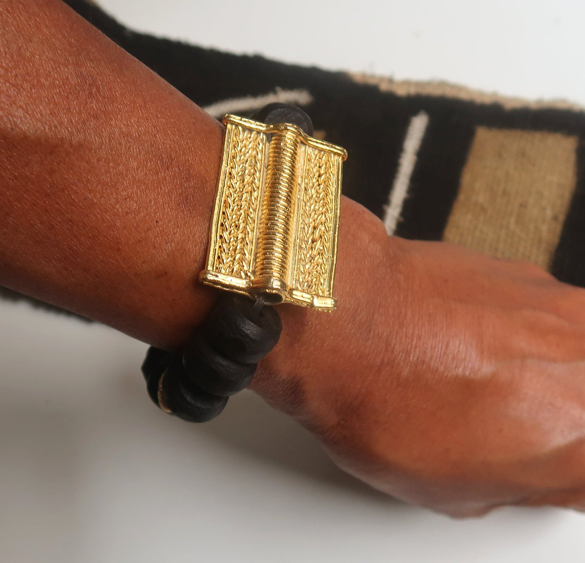 Bracelet mixte en perles de bois et poids Akan rectangle en bronze, porté au poignet