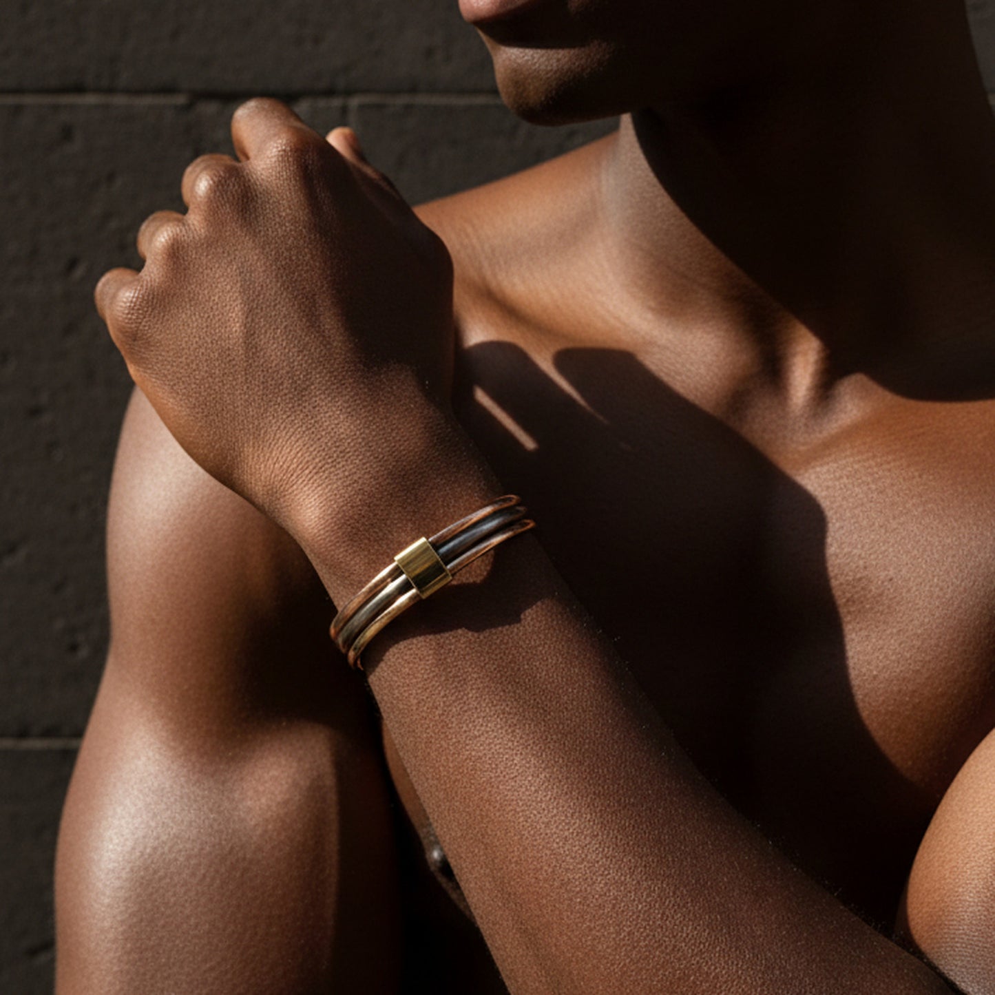 Bracelet Lamou Ndiaxass trois métaux au poignet d'un homme, en lumière rasante