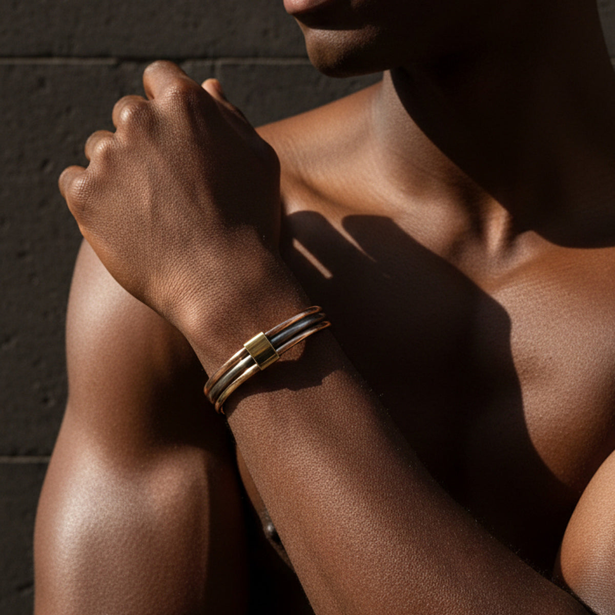 Bracelet Lamou Ndiaxass trois métaux au poignet d'un homme, en lumière rasante