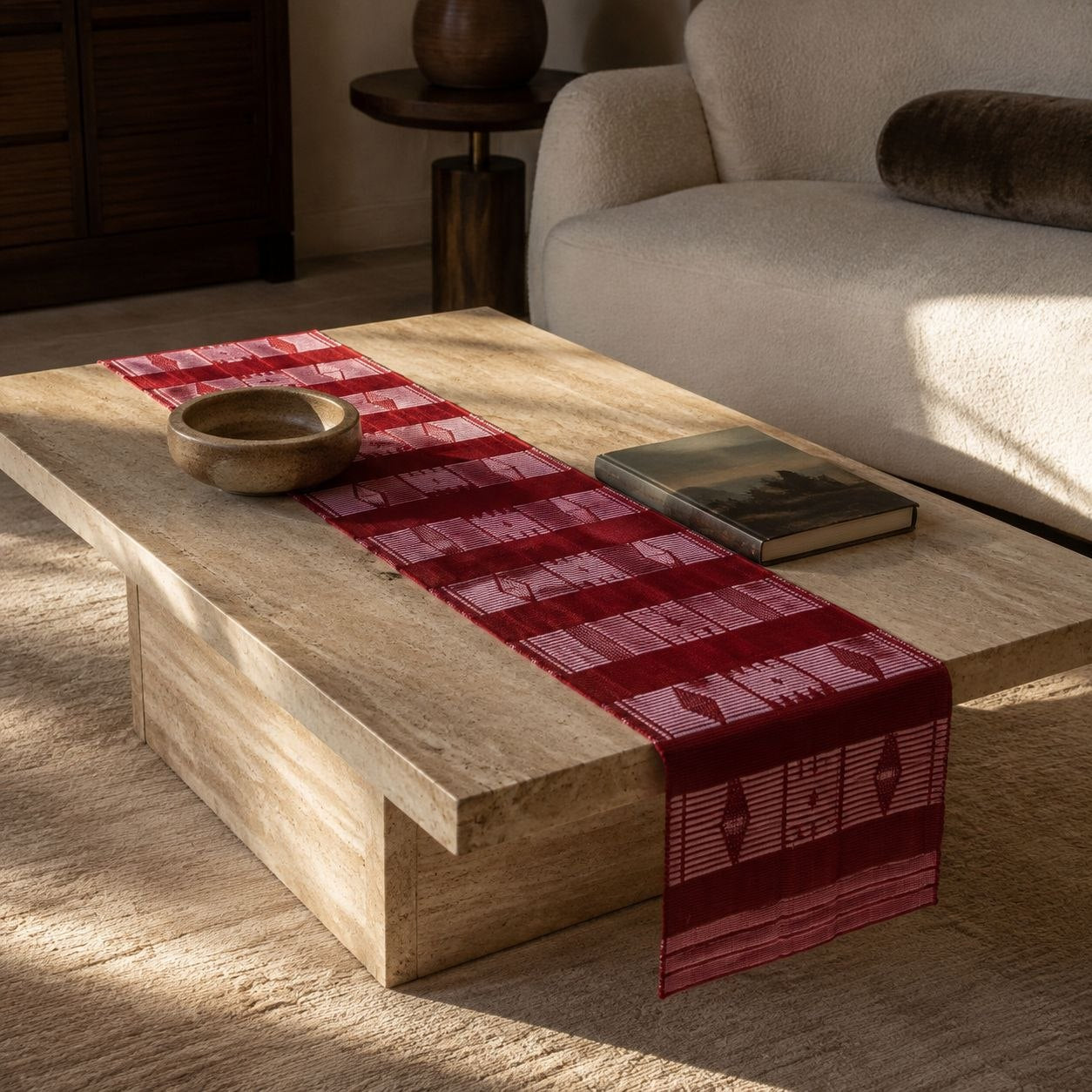 Chemin de table rouge foncé sur une table basse en travertin, retombant sur le côté
