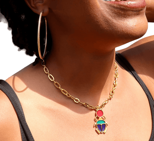 Femme portant le collier Kheper doré à gros maillons, pendentif scarabée émaillé rouge, bleu et or