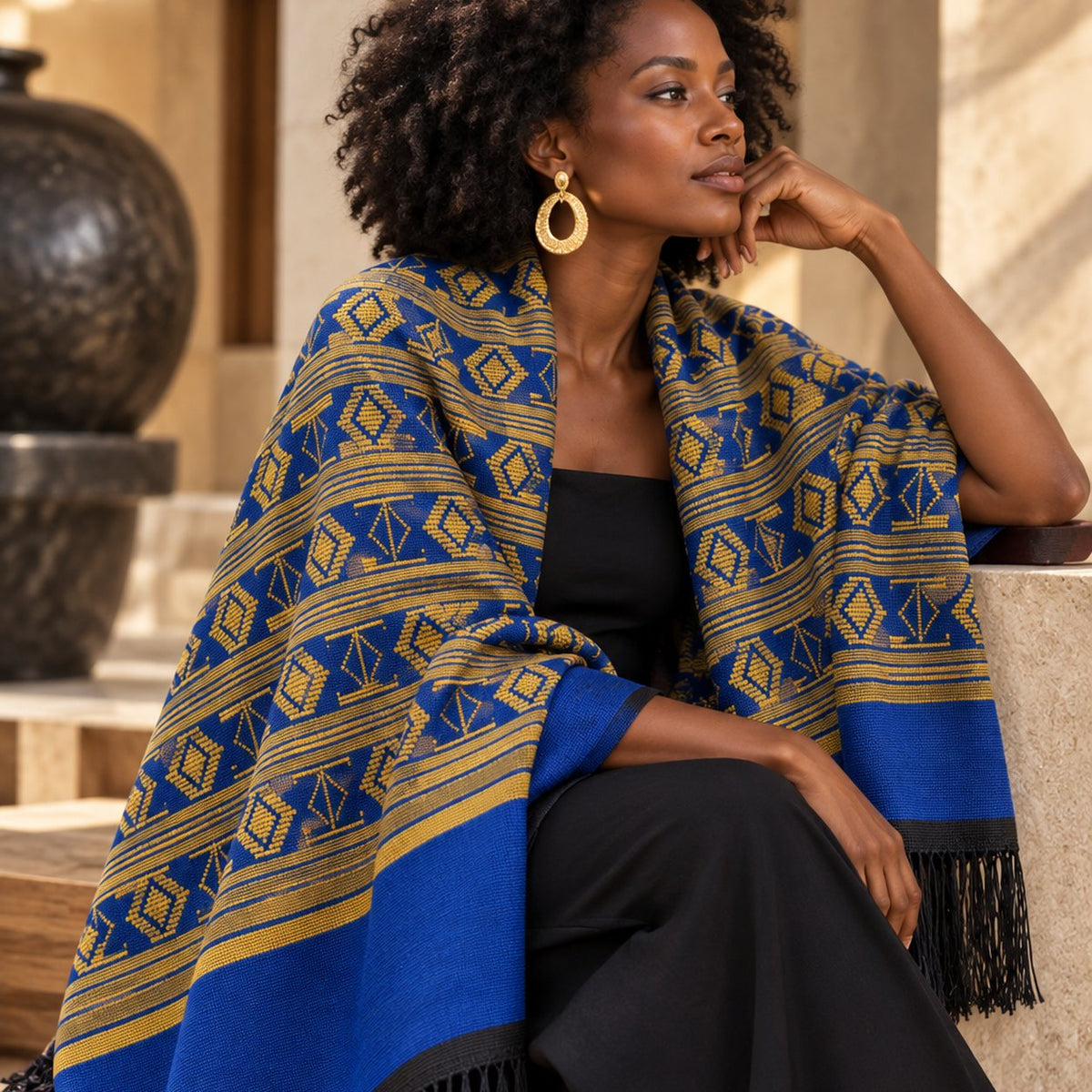 Écharpe-étole Manjak de Luxe bleu roi et jaune doré portée en châle sur les épaules par une femme en robe noire – grand format 78 cm de large