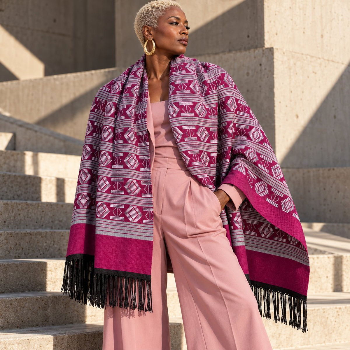 Écharpe-étole Manjak de Luxe fuchsia et blanc portée en châle sur les épaules par une femme en tailleur rose – grand format 78 cm de large