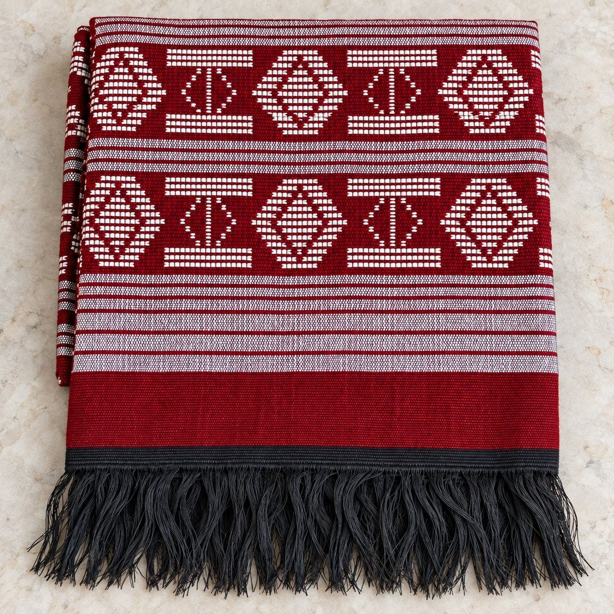 Écharpe Manjak de Luxe rouge pliée, motifs blancs tissés main et franges noires