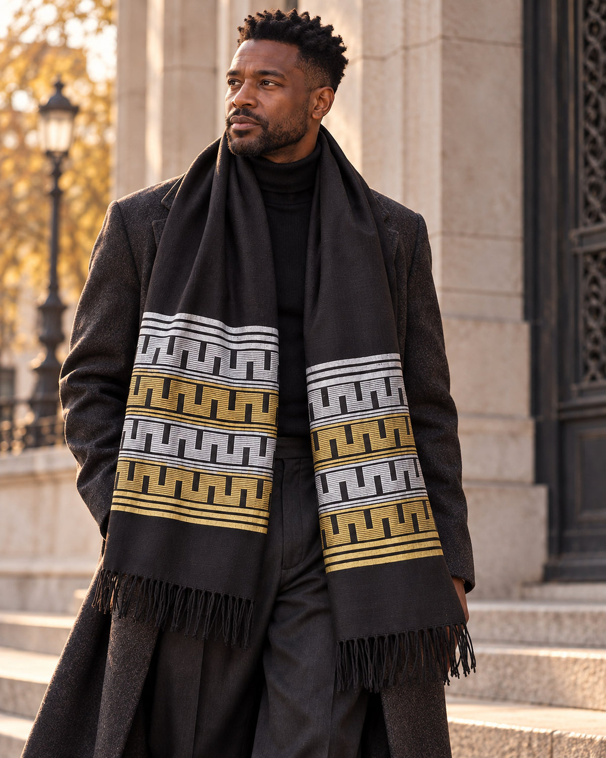 Homme portant l'écharpe Manjak noire à bandes argent et or sur un manteau d'hiver