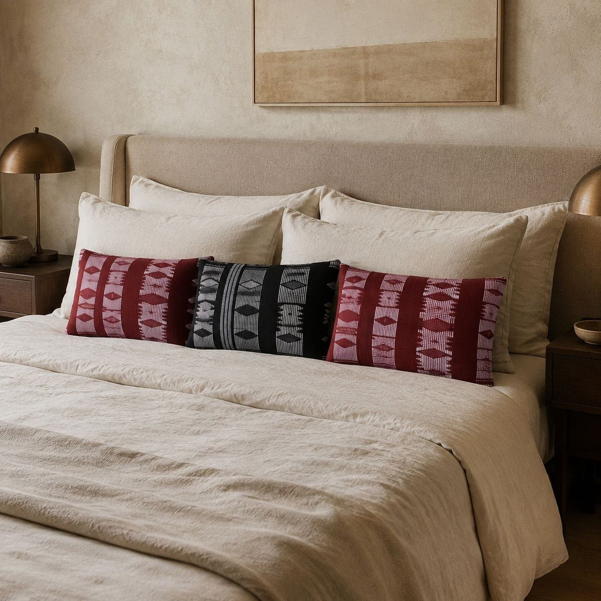 Housses de coussin Manjak rouge foncé et noir et blanc devant les oreillers d'un lit en lin