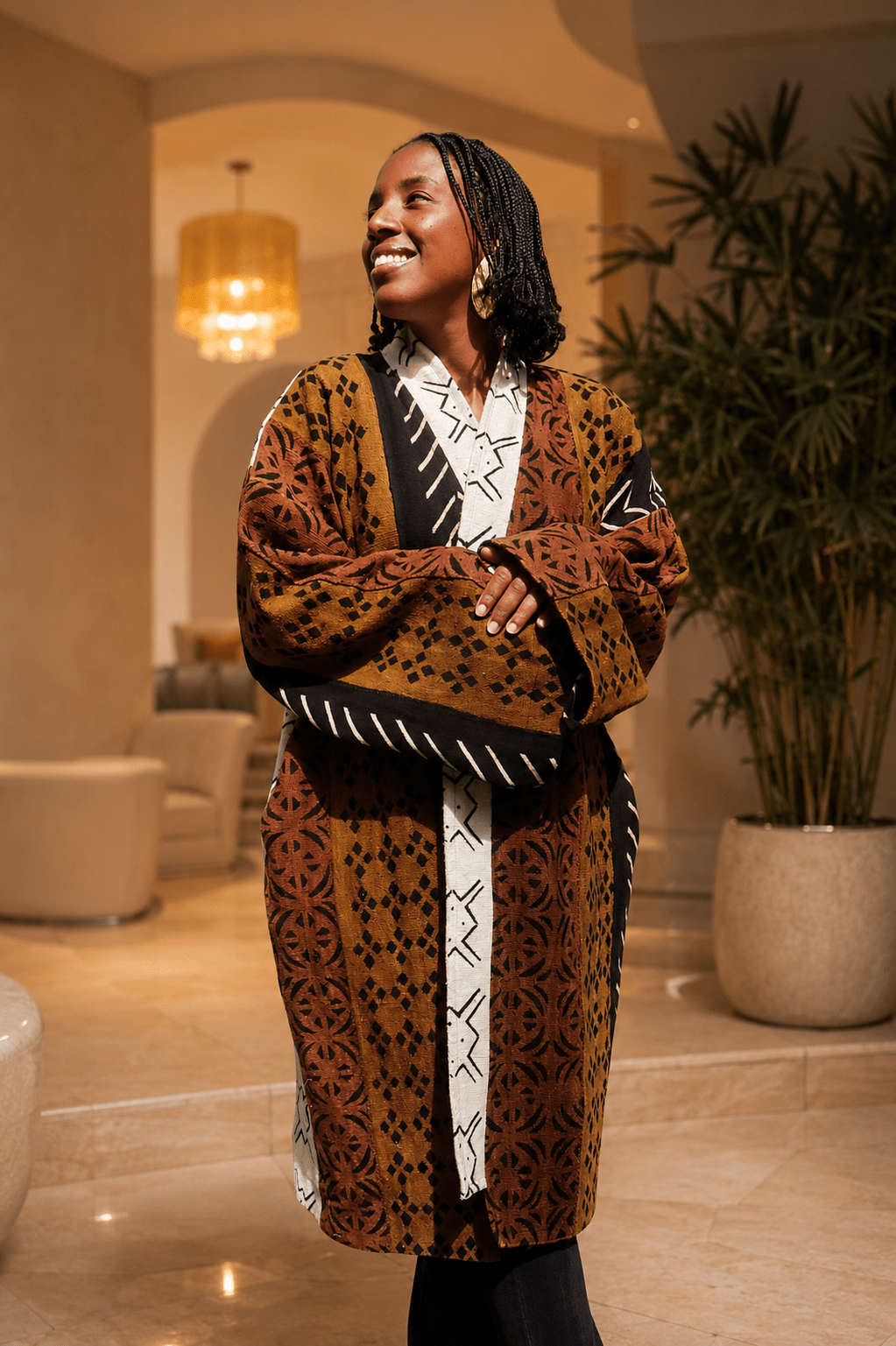 Femme portant un manteau kimono en bogolan artisanal africain fermé et ceinturé, manteau long en coton tissé doublé, motifs traditionnels marron, noir et écru, création Kaolack Créations.