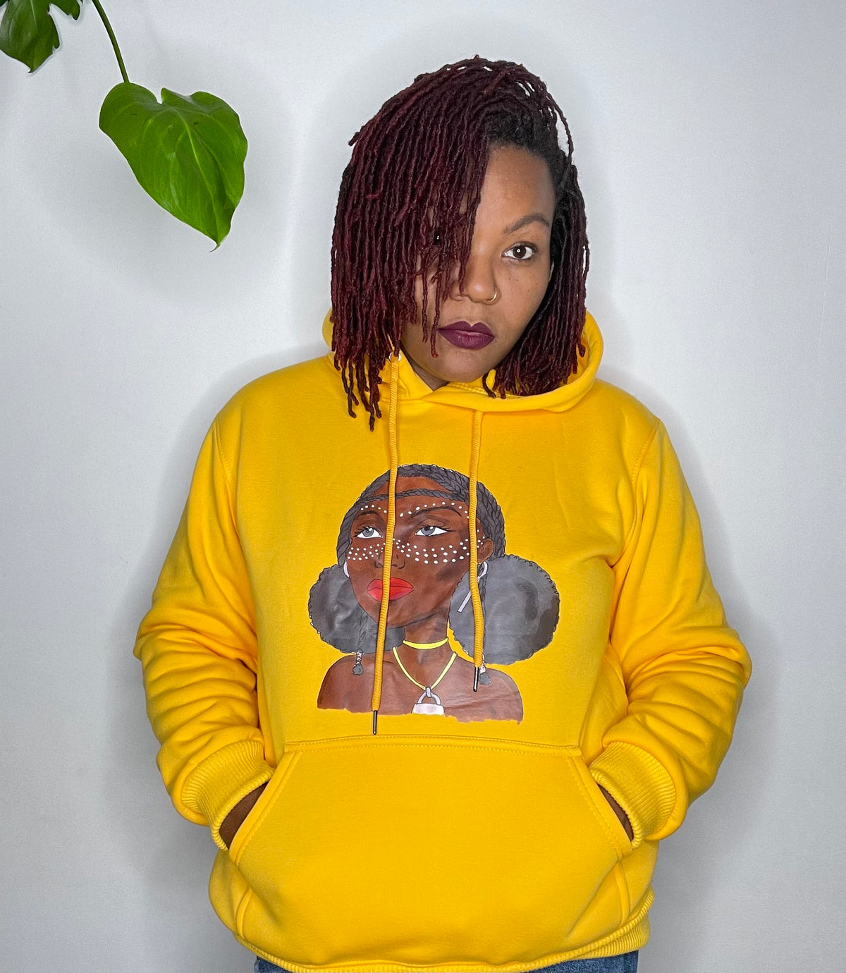 Femme portant le sweat à capuche jaune Grandeur Noire, motif Amina