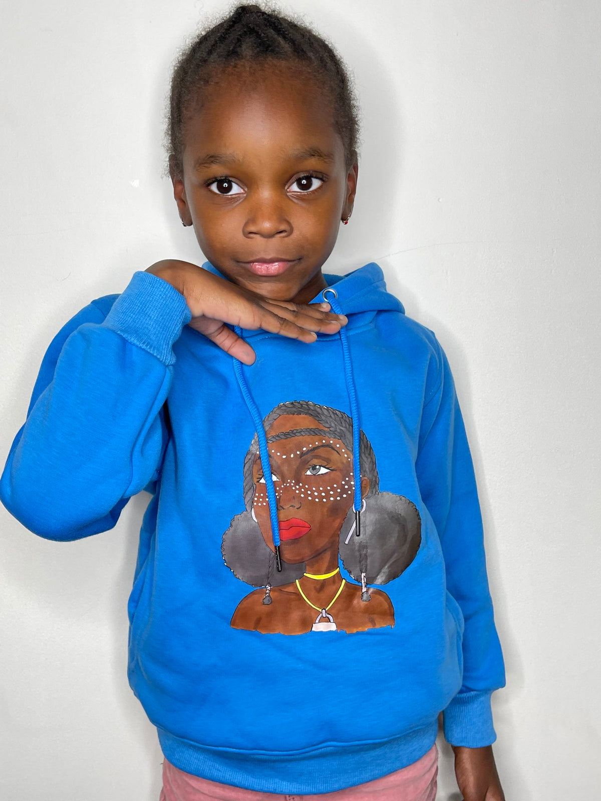 Fillette posant en sweat à capuche bleu Grandeur Noire, motif Amina