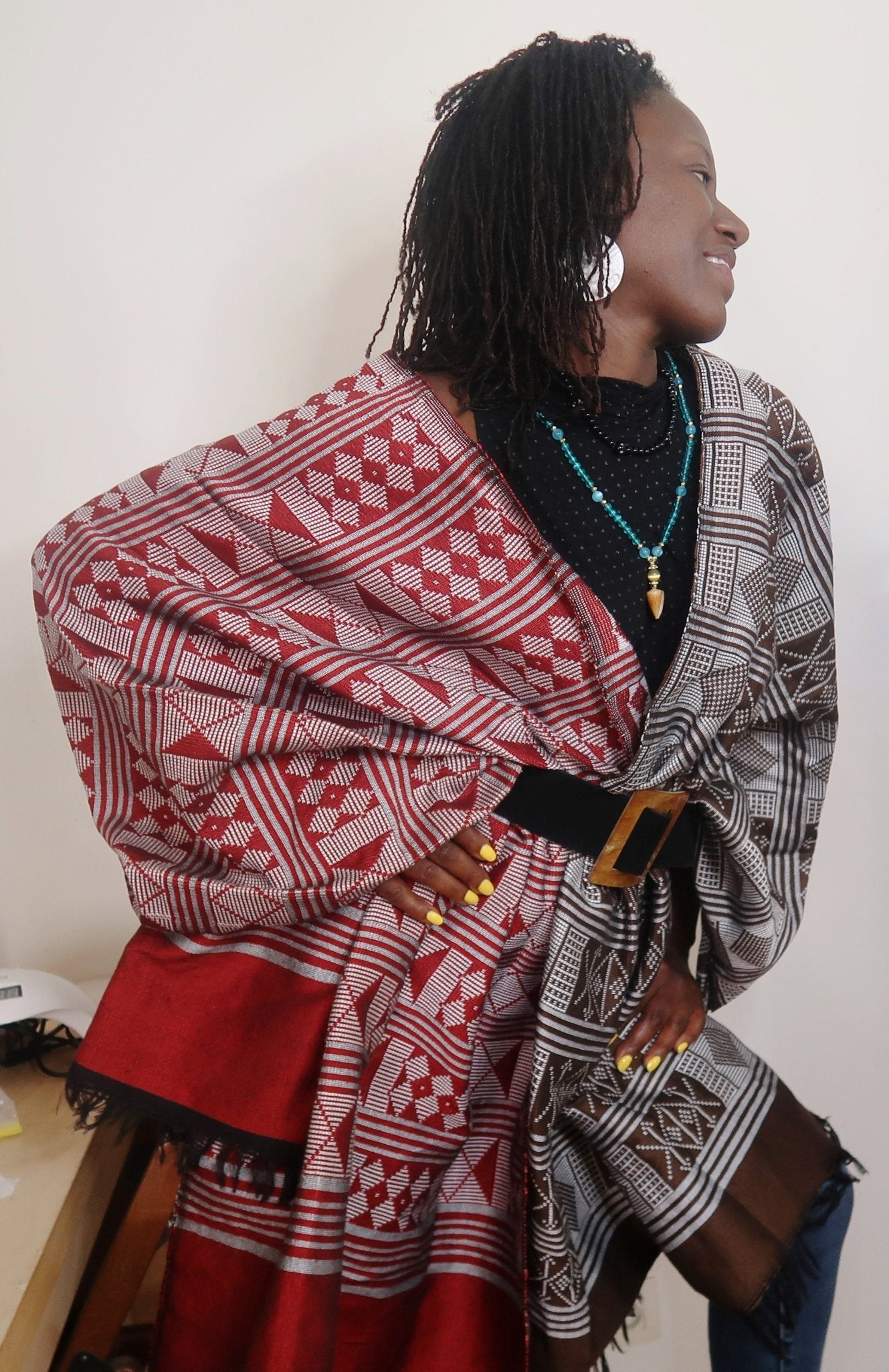 Femme portant une étole Manjak de luxe rouge profond, tissée main en coton artisanal — pagne africain de Casamance, édition très limitée 